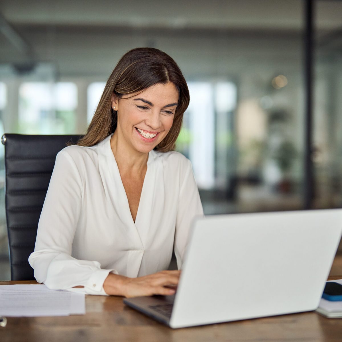 Happy cheerful mid aged business woman executive in office using laptop at work, smiling professional mature 40 years old female company manager working on computer at workplace.
